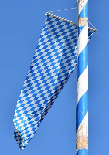 Ein Maibaum in Bayern mit den bayerischen Farben und Flagge