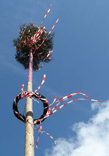 Ein Maibaum mit roten und weißen Bändern